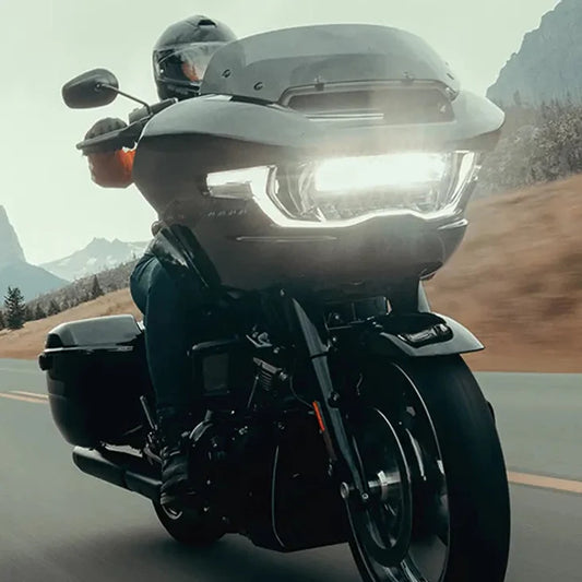 Harley-Davidson Road Glide with headlights on, riding a mountain road