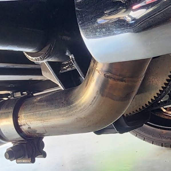 Close-up of a motorcycle exhaust system on a concrete floor.
