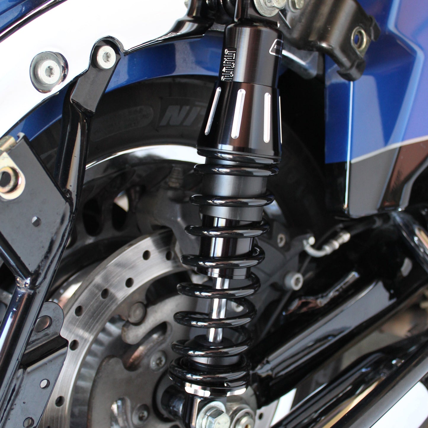 Close-up of a motorcycle's suspension system with blue and black color scheme.